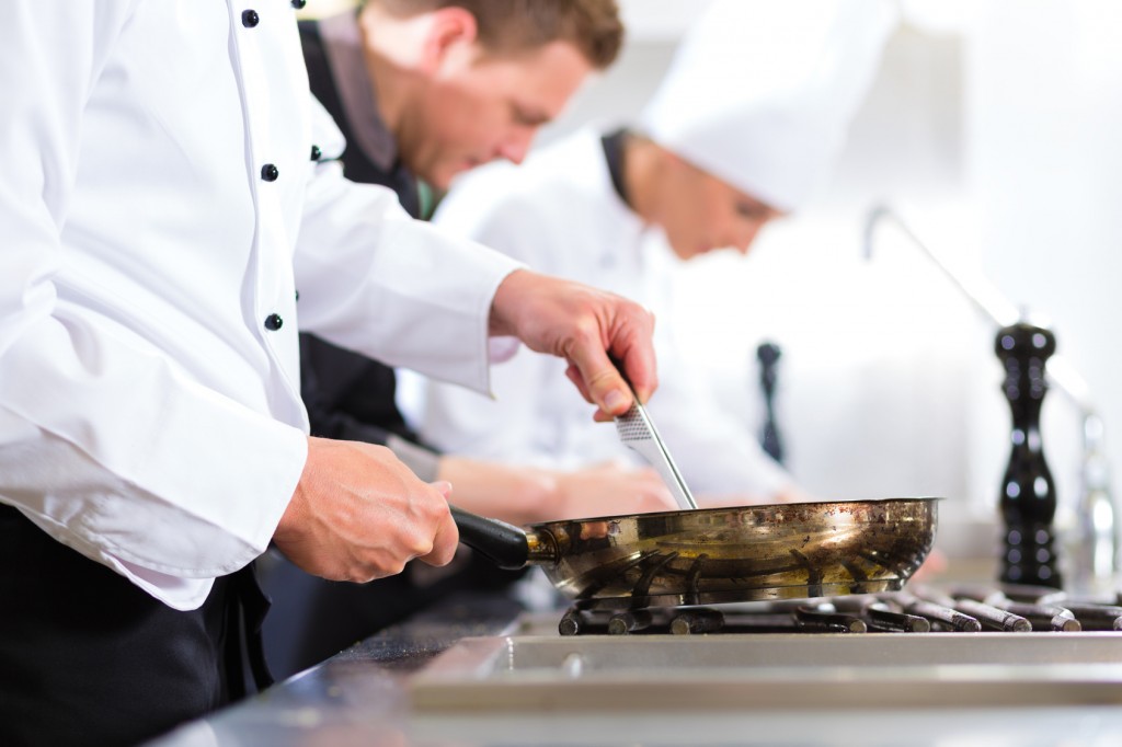 Three chefs in team in hotel or restaurant kitchen