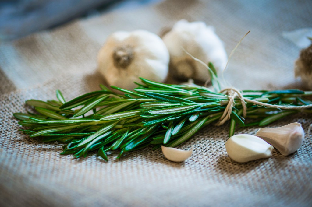 Fresh rosemary with fresh garlic on wooden background